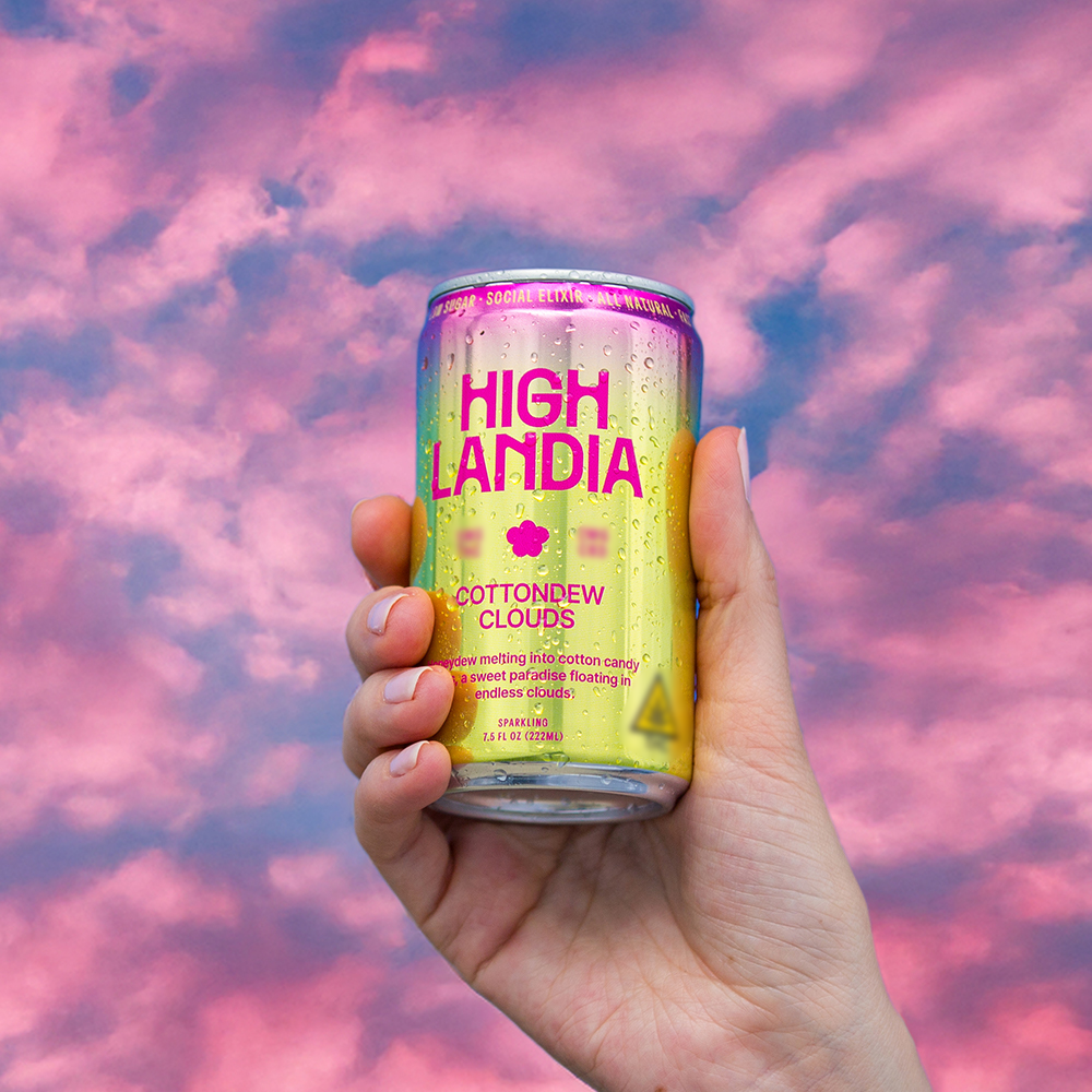 Hand holding Cottondew Clouds 5mg THC drink against a pink cotton-candy sky background