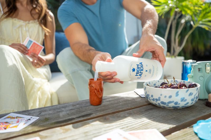 Couple pouring Free Spirit 10mg THC mixer into a cup at a sunny outdoor moment